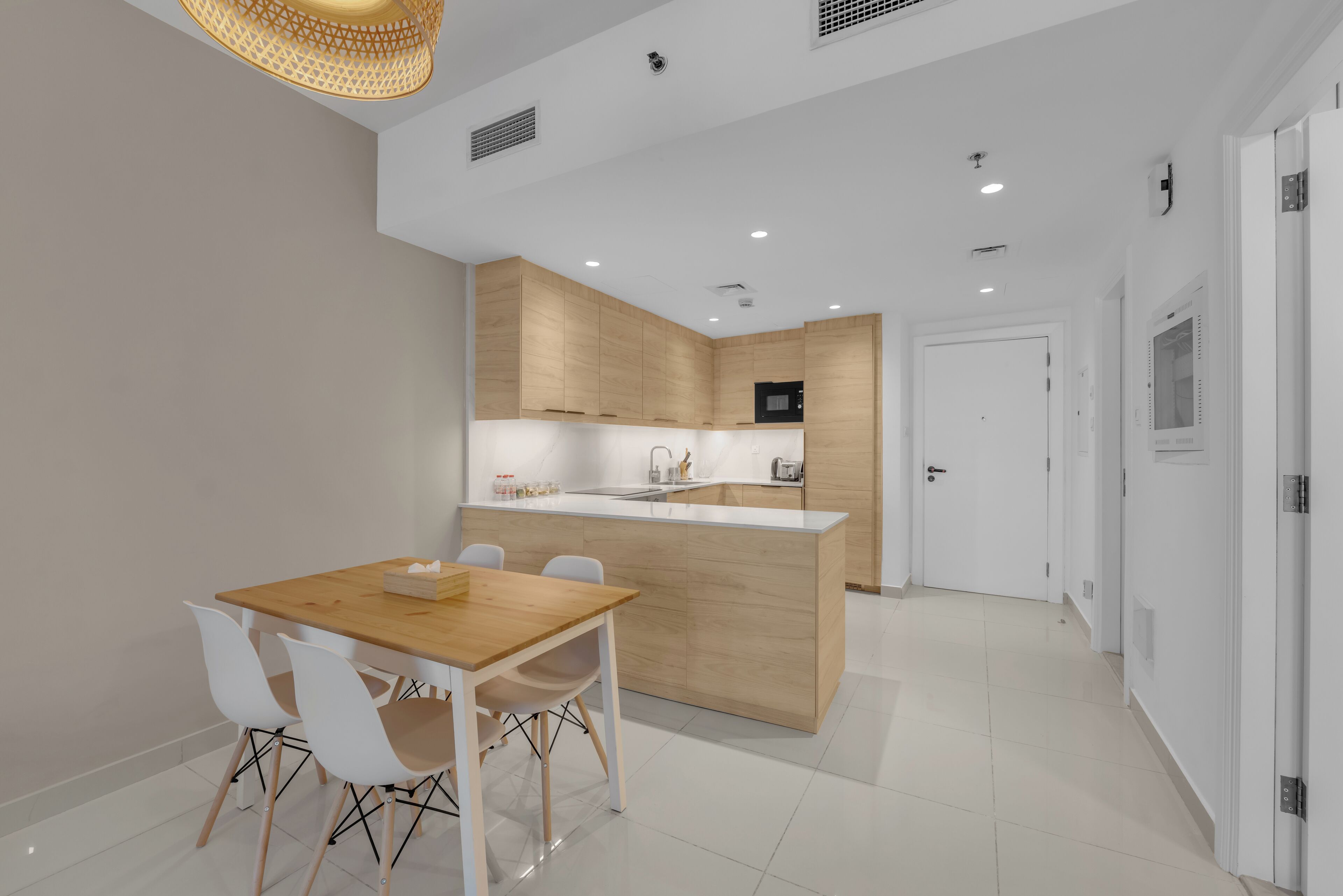A modern kitchen with a wooden island, white cabinetry, and a dining area with a wooden table and white chairs.