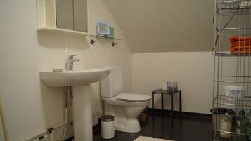 A small bathroom with a sink, toilet, and a small table with toiletries.