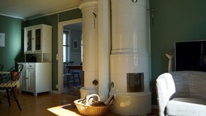Une pièce dans laquelle se trouve un grand objet cylindrique blanc, qui pourrait être un chauffe-eau, près d’une fenêtre. On y voit également un panier en osier posé sur le sol et un meuble blanc avec des portes en verre.