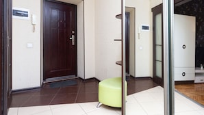 A hotel lobby with a dark wooden door, a green cushioned bench, and a glass partition.
