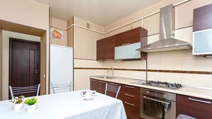 A compact kitchen with a dining area, including a table with chairs, a refrigerator, a stove, and cabinets.