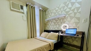 Une chambre d’hôtel avec un lit, un bureau doté d’un ordinateur portable, un anneau lumineux et un mur orné d’un motif géométrique.