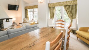 Ein gemütliches Wohnzimmer mit einem Holzesstisch, einer grauen Couch und einem gelben Sessel.