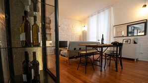 Un coin repas avec une table en bois, des chaises et un meuble vitré contenant des bouteilles de vin.
