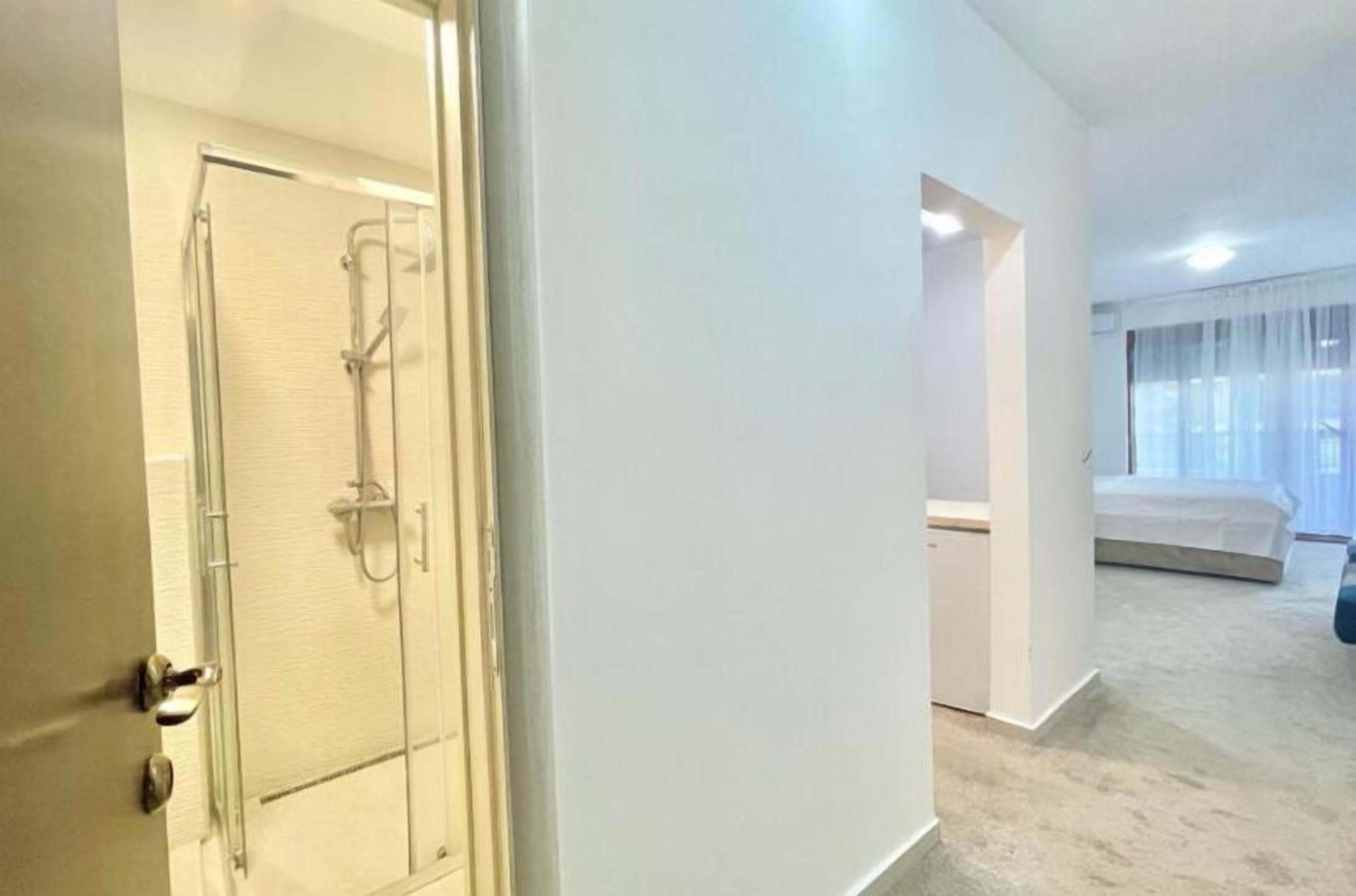 Habitación de hotel con ducha, cama y ventana con cortinas.