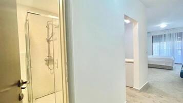 Habitación de hotel con ducha, cama y ventana con cortinas.