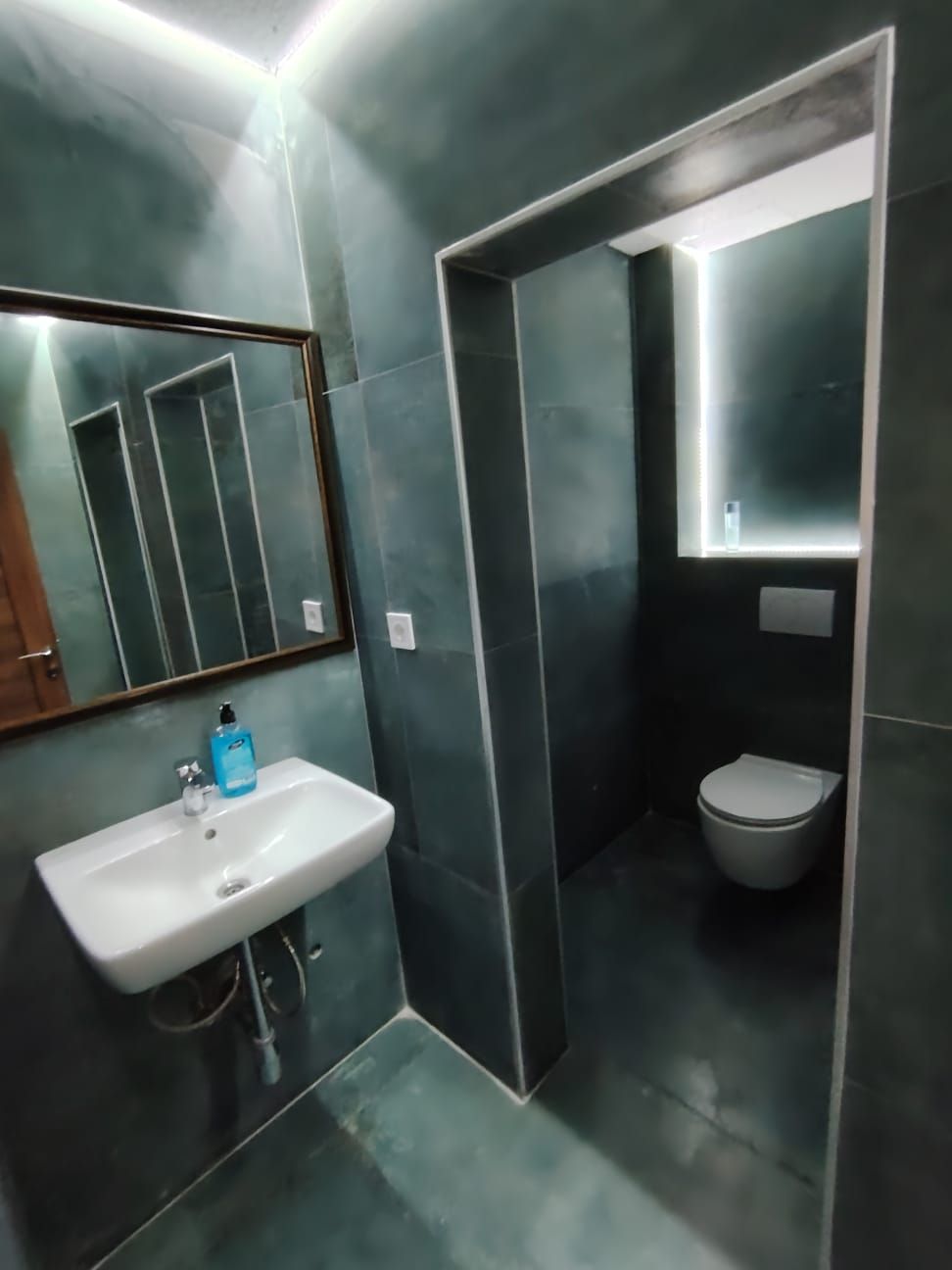 Un baño moderno con un lavabo blanco, un espejo y un inodoro.