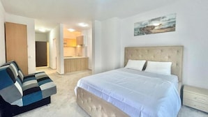 Un dormitorio con una cama grande, un sofá, una zona de cocina y un baño.