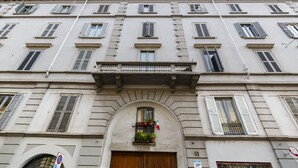 Ein Gebäude mit zahlreichen Fenstern, einem zentralen Bogenportal und einem Balkon.