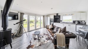 Un salon moderne avec une cheminée, un canapé, un coin repas et une cuisine.