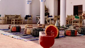 A traditional Moroccan interior with arches, cushions, and a table with a drink. - Riad Bounaylat (Addiss)