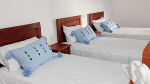 A hotel room with two single beds, wooden headboards, white bedding, and blue decorative pillows. - Riad Bounaylat (Addiss)