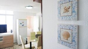 Um quarto com uma mesa de jantar, cadeiras, televisão e geladeira.