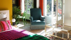 A bedroom with a bed, a chair, a table, and a large window.