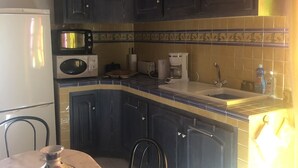 A kitchen with dark cabinets, a microwave, a coffee maker, and a sink. - Studio Equipe a Proximite Plages et Commerces (Six-Fours-les-Plages)