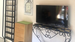 A room with a TV on a decorative stand, a wooden cabinet, a ladder, and a metal railing. - Studio Equipe a Proximite Plages et Commerces (Six-Fours-les-Plages)