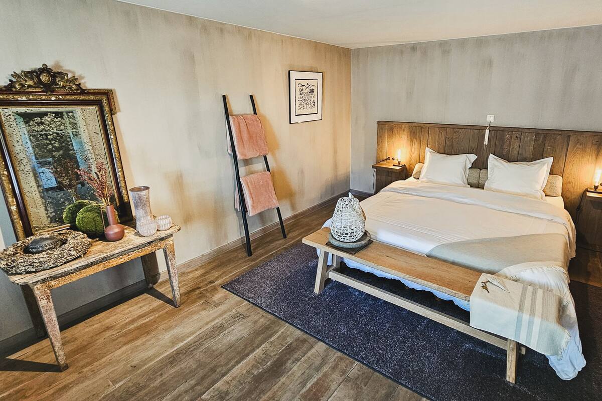 Une chambre à coucher avec un lit en bois, des tables de chevet, un miroir et un porte-serviettes fixé au mur.