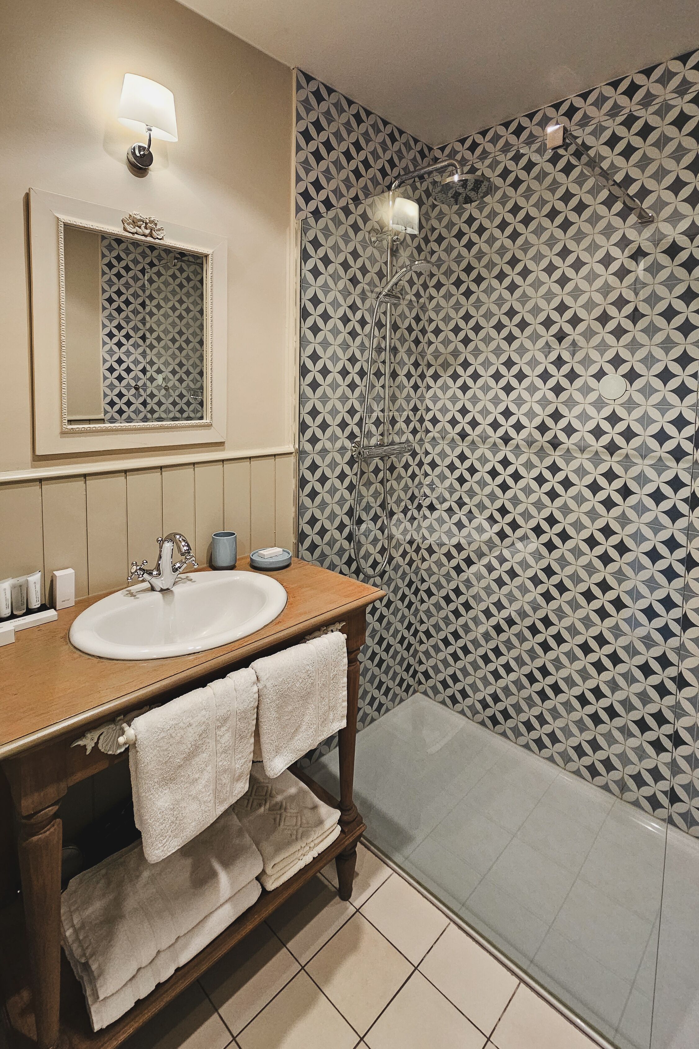 A bathroom with a sink, mirror, and shower.