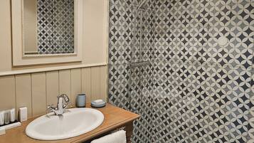 A bathroom with a sink, mirror, and shower.