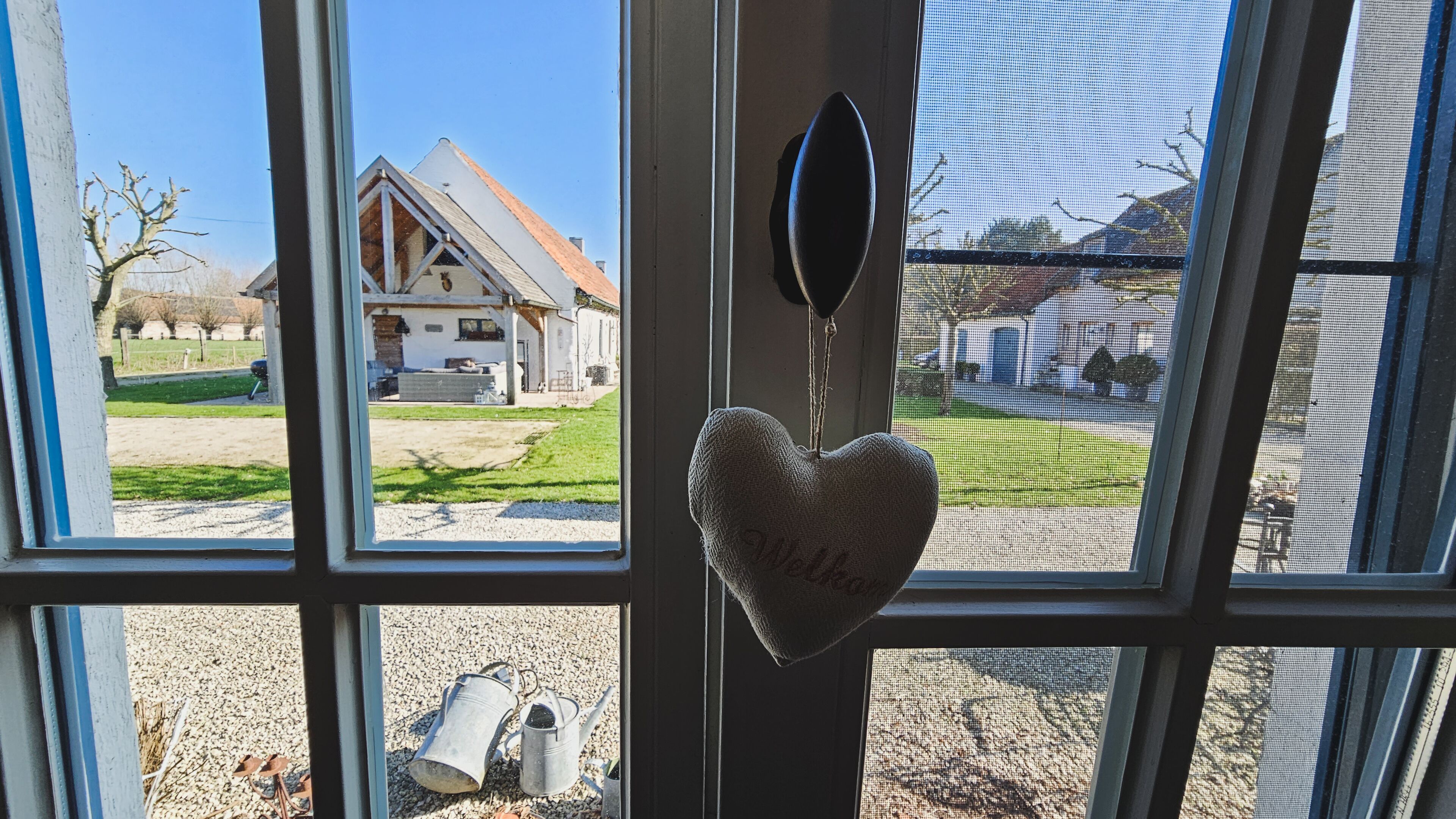 A window with a heart-shaped decoration and a metal object on the sill.