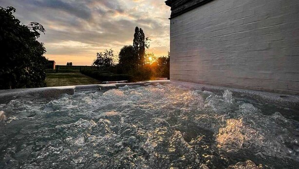 Ein Whirlpool mit Blick auf einen Sonnenuntergang und ein Gebäude im Hintergrund.