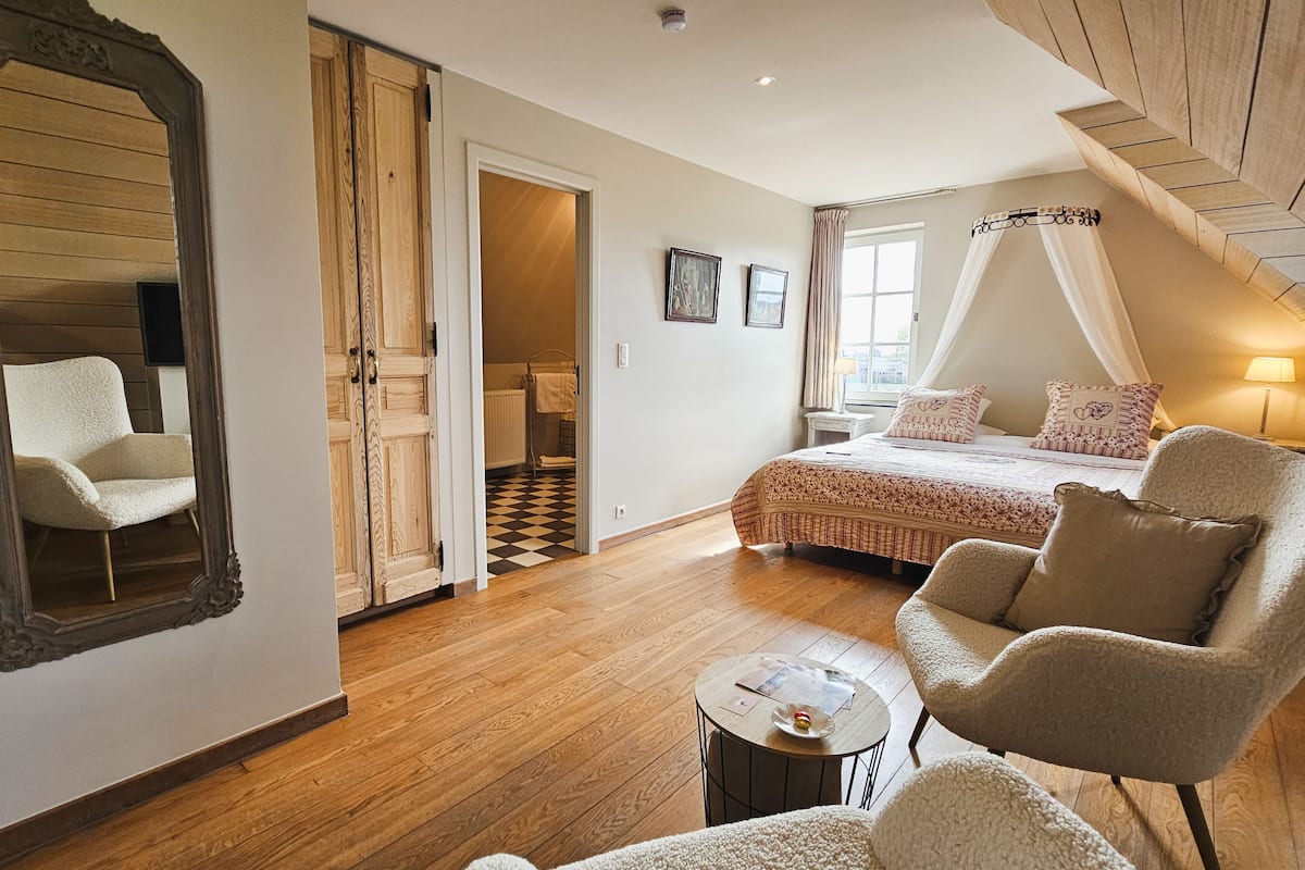Une chambre à coucher avec un lit, une chaise, une table et un miroir.