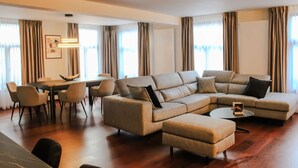 A modern living room with a sectional sofa, a dining table with chairs, and large windows with curtains. - Modern and Stylish! Luxury apartment for 7 in the center of Antwerp. (Antwerp)