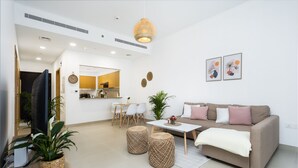A modern living room with a sofa, coffee table, and dining area. - Waves - Chic Apartment With Dubai Skyline Views (Dubai)