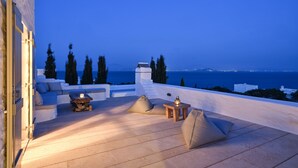 A terrace with a view of the sea, featuring a sofa, a table, and a lamp. - VILLA EKAVI FILIZI - Seaside Residence just outside of Naousa (Naousa)