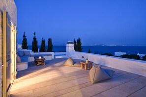 Eine Terrasse mit Meerblick, ausgestattet mit einer Couch, einem Tisch und einer Lampe.