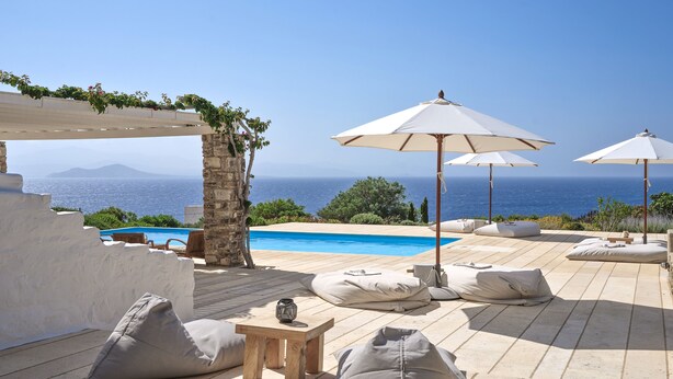 A sunlit outdoor seating area with a pool, stone walls, and a view of the sea. - VILLA EKAVI FILIZI - Seaside Residence just outside of Naousa (Naousa)