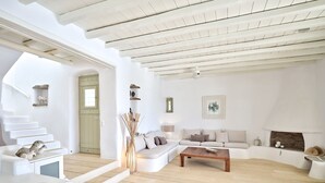 A spacious living area with a high ceiling, white walls, and a wooden floor. There is a staircase leading to an upper level, a sofa set, and a coffee table. - VILLA EKAVI FILIZI - Seaside Residence just outside of Naousa (Naousa)