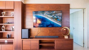 Uma sala de estar moderna com uma grande televisão de tela plana fixada em uma parede de madeira, um móvel embutido para entretenimento e objetos decorativos.
