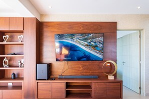 Un soggiorno moderno con una grande TV a schermo piatto montata su una parete in legno, un mobile TV a incasso e decorazioni.