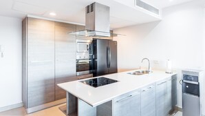 Cozinha moderna com eletrodomésticos de aço inoxidável, coifa de vidro e filtro de água embutido.