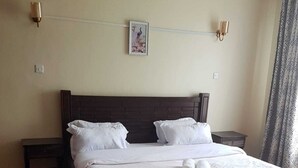 A bedroom with a wooden bed, white bedding, two bedside tables, and a red throw blanket. - 3-bed Apartment in Nanyuki With Golf Course Views (Nanyuki)