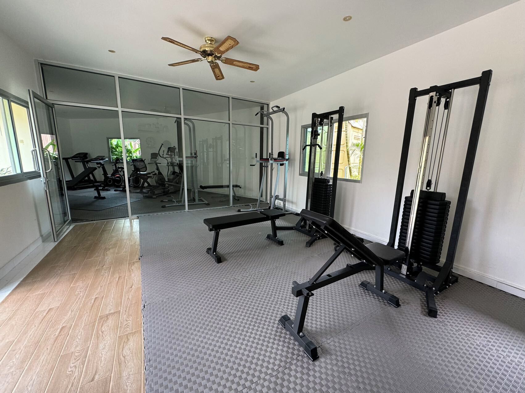 A modern gym with a ceiling fan, exercise equipment, and a large window.