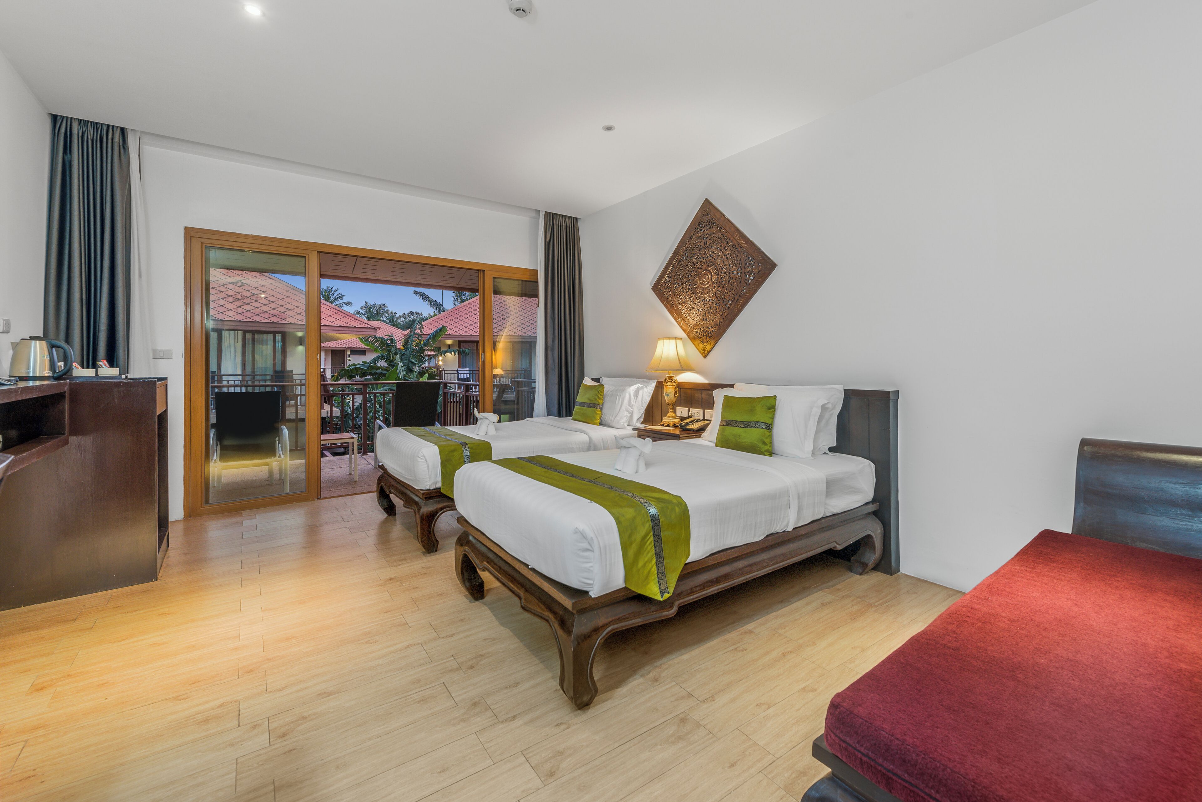 A hotel room with a large bed, two bedside tables, a desk, and a view of the outdoor area.
