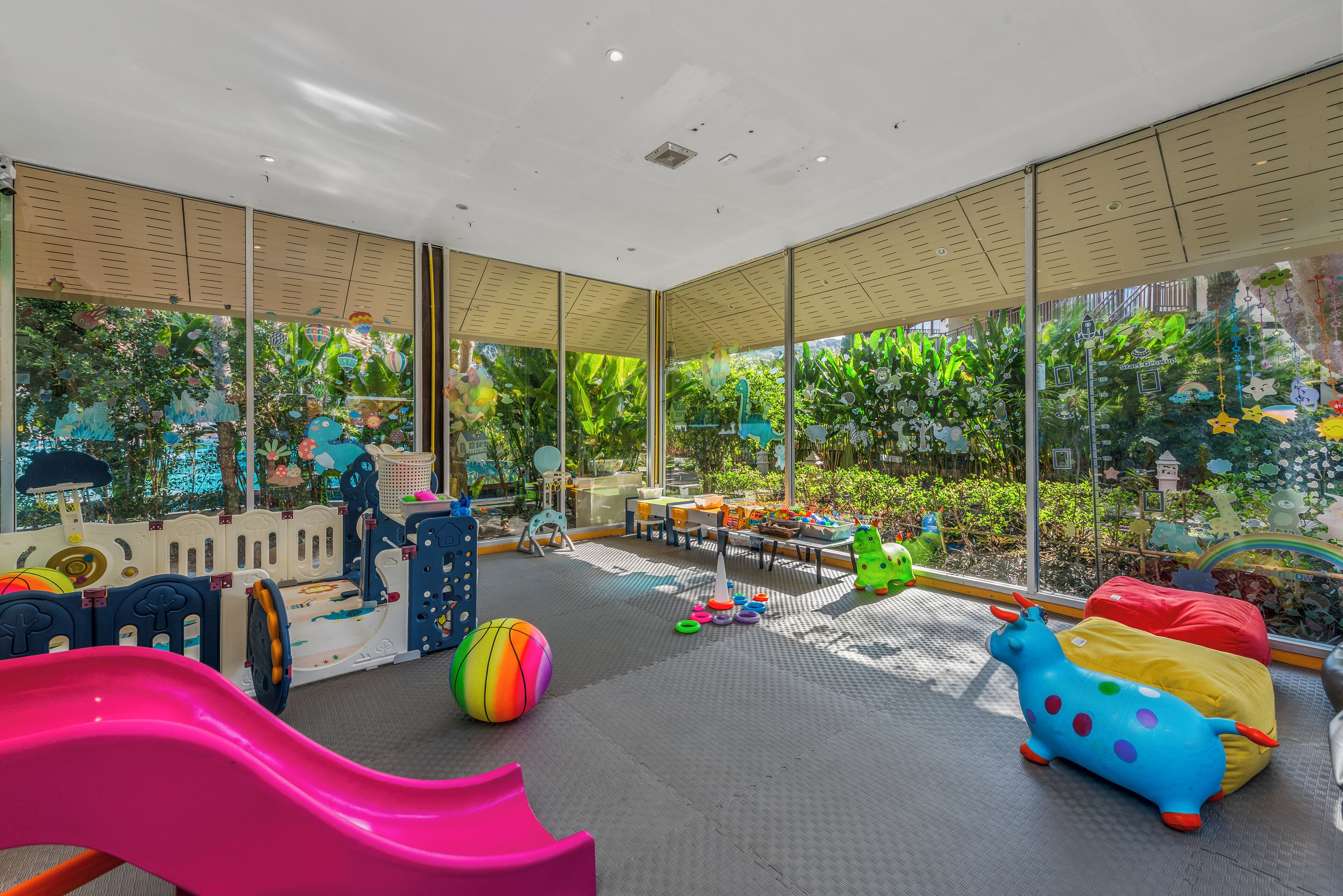 Un espace de jeux pour enfants avec un toboggan, des tapis de jeu et des jouets colorés.