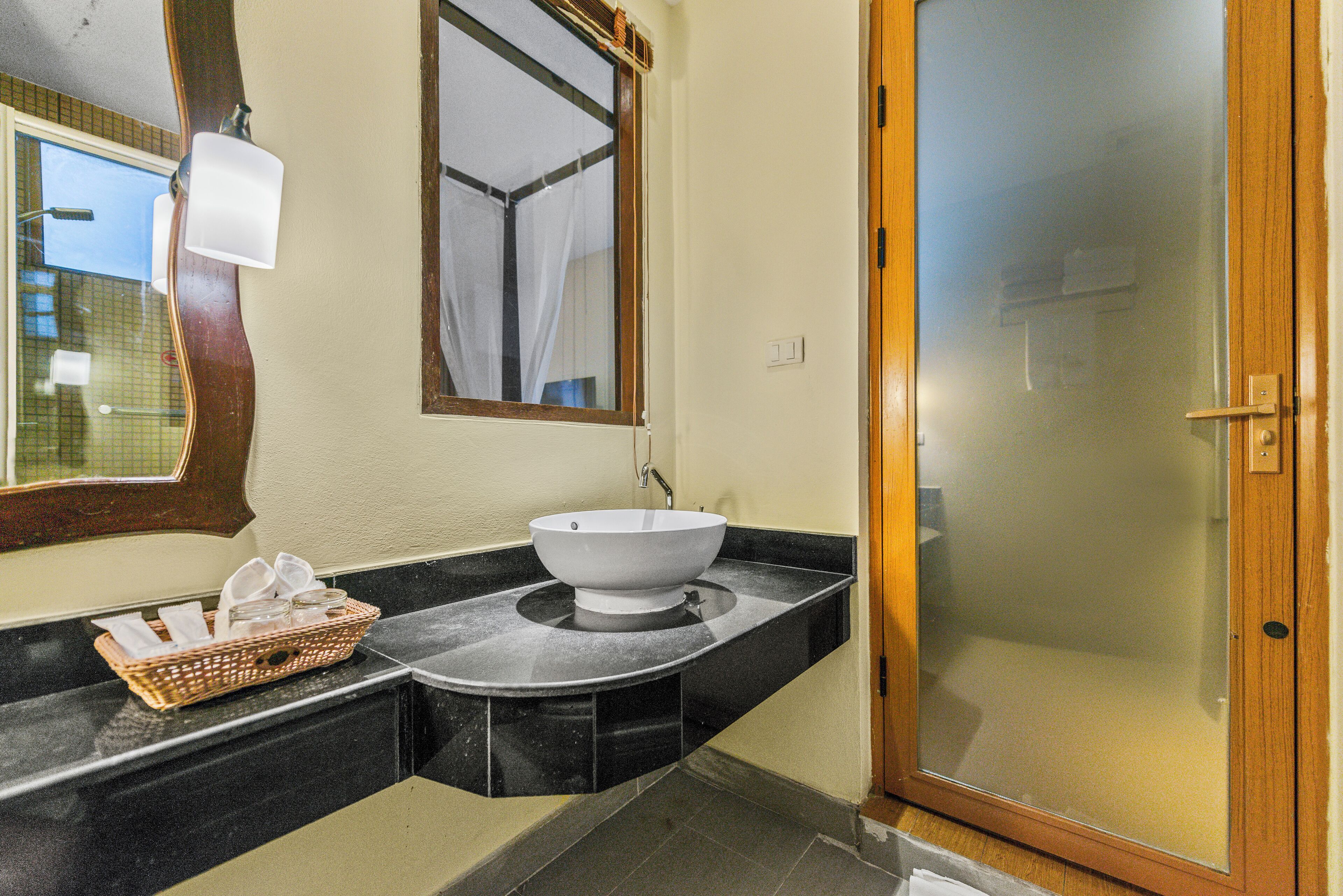 A bathroom with a white sink, a mirror, and a wooden door.