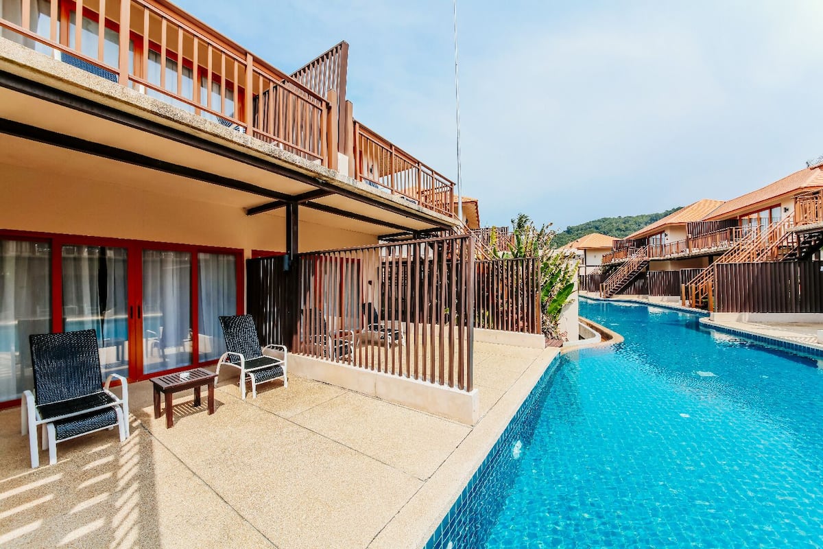A hotel with a swimming pool, outdoor seating, and a view of the surrounding landscape.
