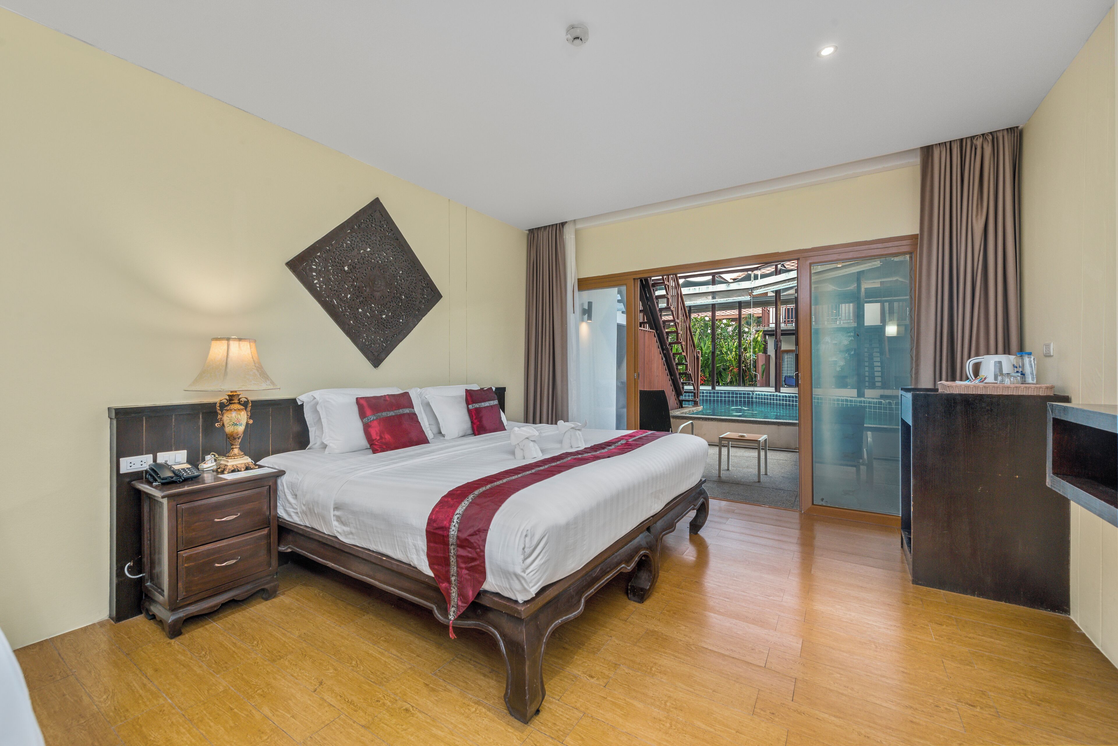 A hotel room with a large bed, a nightstand, a desk, and a view of a pool and outdoor area.