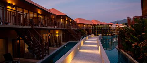 A hotel with multiple balconies, a central pool, and a staircase leading to the upper floors.