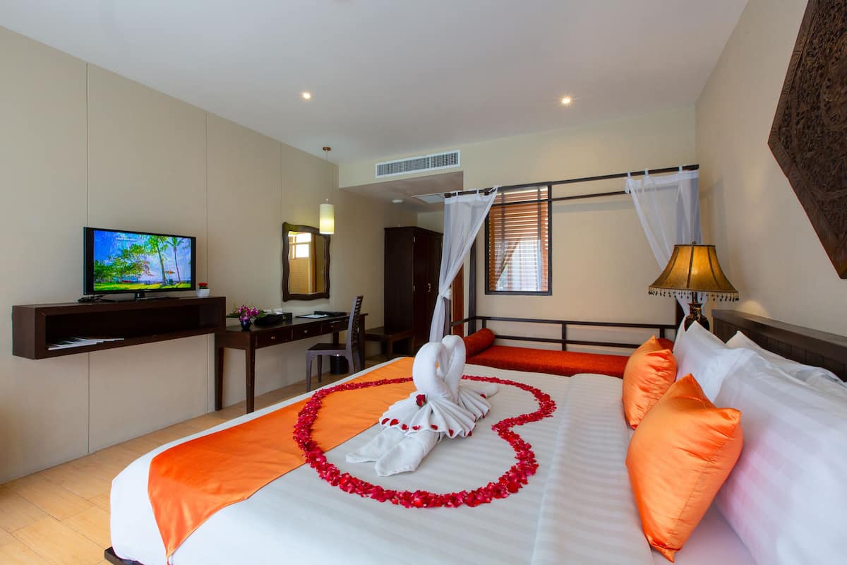 A hotel room with a bed, a desk, a television, and a window with blinds.