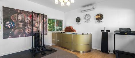A modern gym with exercise equipment, a large mirror, and clocks displaying different cities.