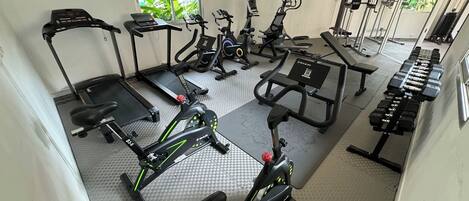 Un gimnàs amb diversos equips d'exercici, incloent cintes de córrer, bicicletes estàtiques i màquines de peses.