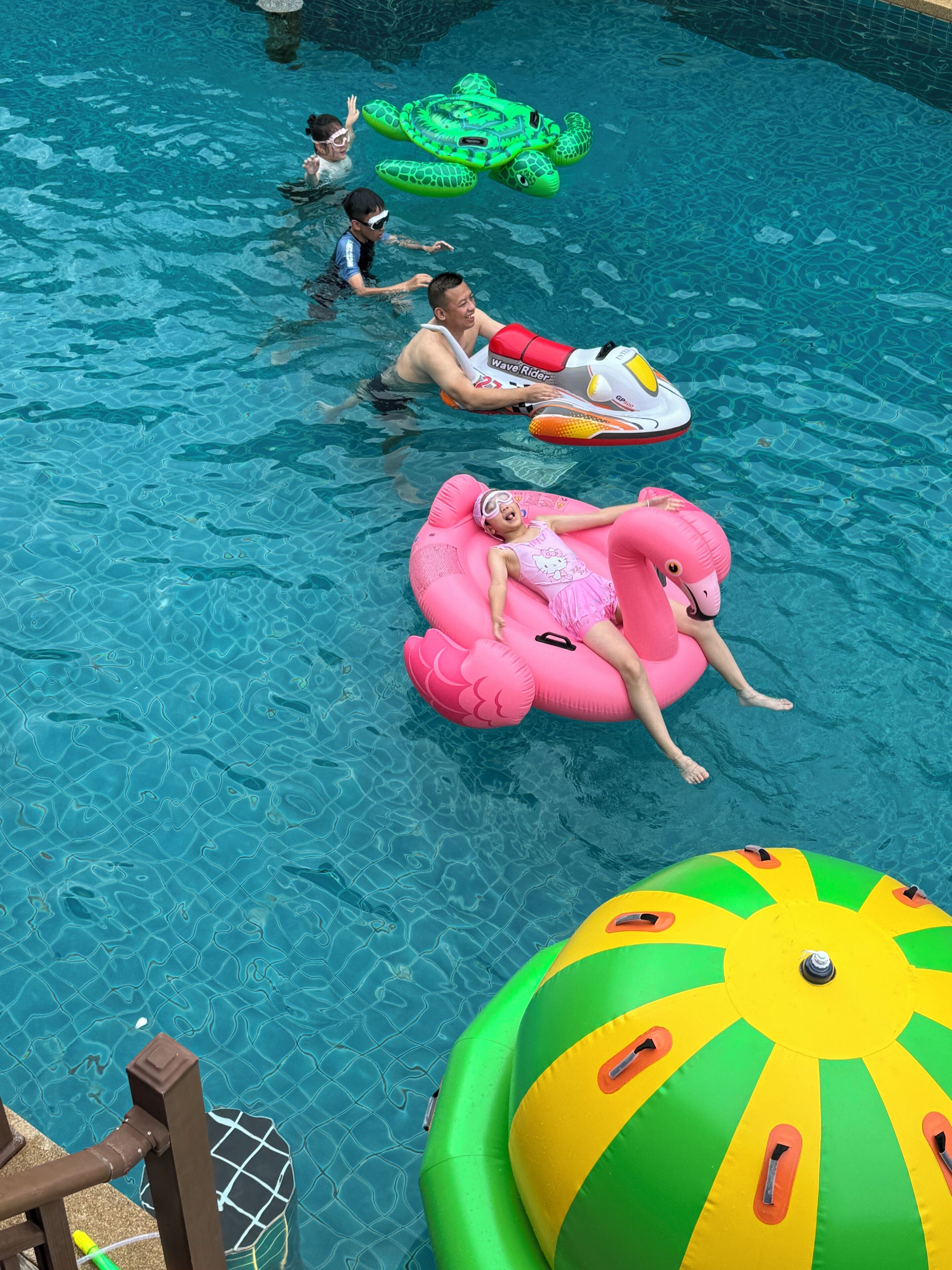 A swimming pool with inflatable toys and a beach umbrella.