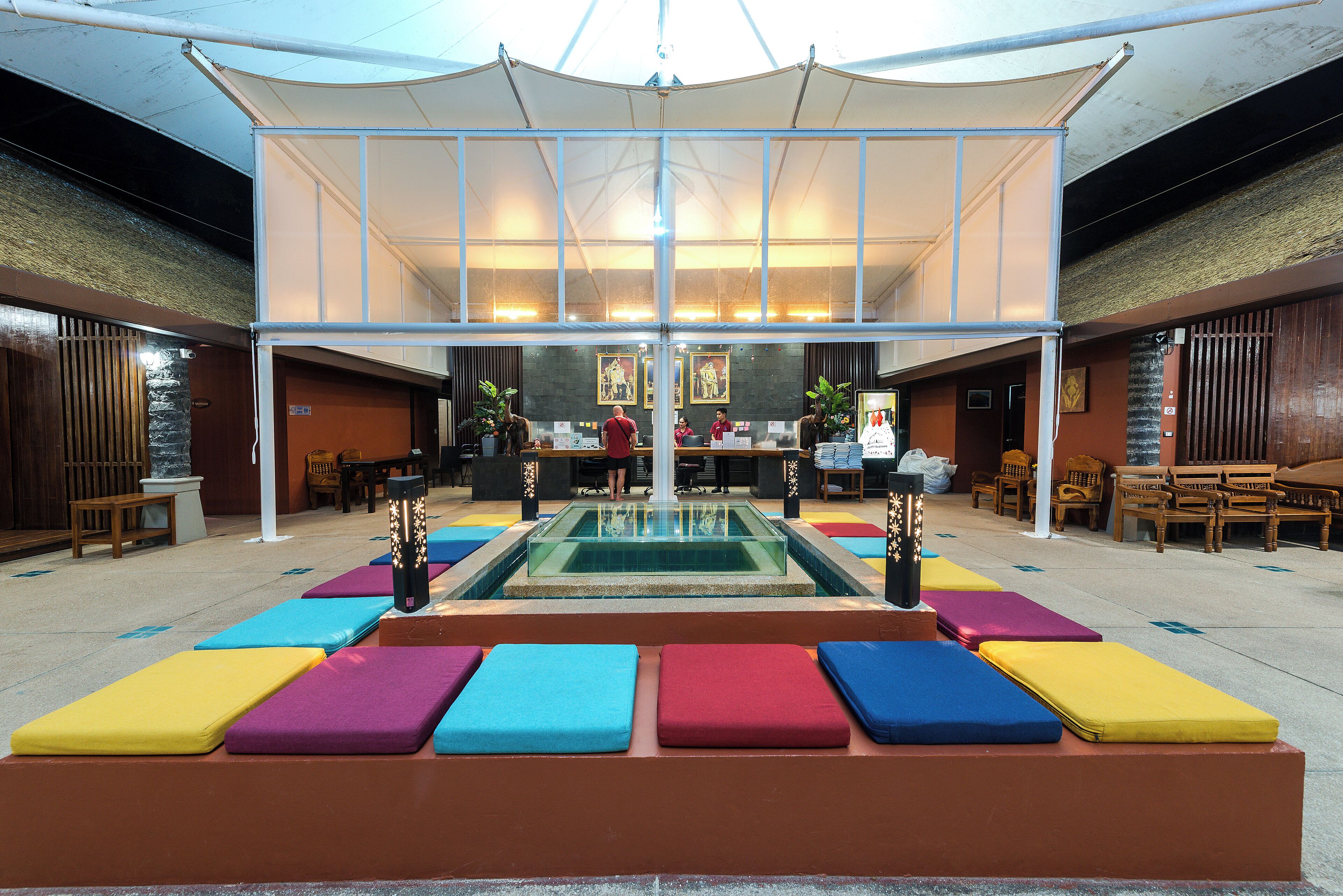 A spacious indoor area with a central pool, colorful seating, and a reception desk.