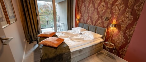 A neatly made bed with pillows, a wooden floor, a balcony with a chair, and patterned wallpaper.