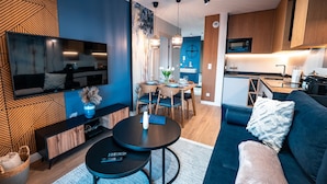 A modern living room with a TV, sofa, and dining area. - Apartamenty Sun & Snow Cicha (Krynica-Zdroj)